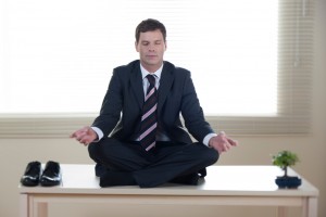 Young businessman meditating on his desk
